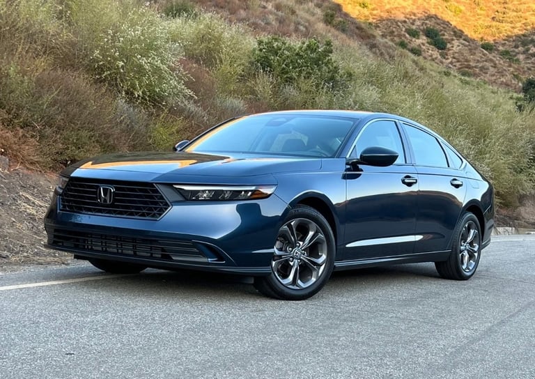 Blue Honda Accord sedan parked on a road with hillside vegetation in the background